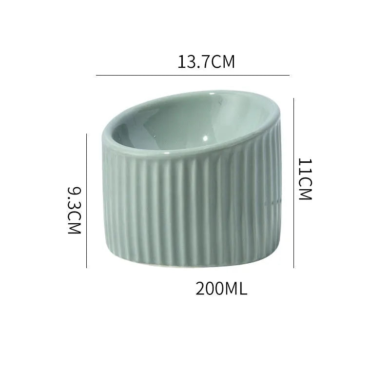 Ceramic elevated cat bowl in green colour showing tilted, round whisker-friendly design.