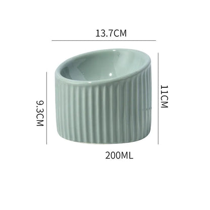 Ceramic elevated cat bowl in green colour showing tilted, round whisker-friendly design.