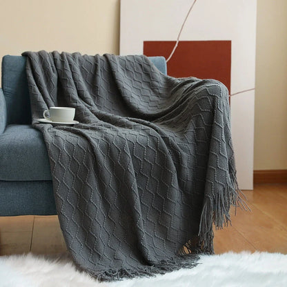 Nordic knitted blanket in beige colour showing open knit pattern on grey sofa