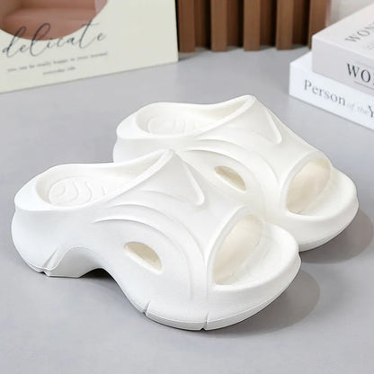 Women's white thick-soled EVA slippers with a round toe on a beach background.