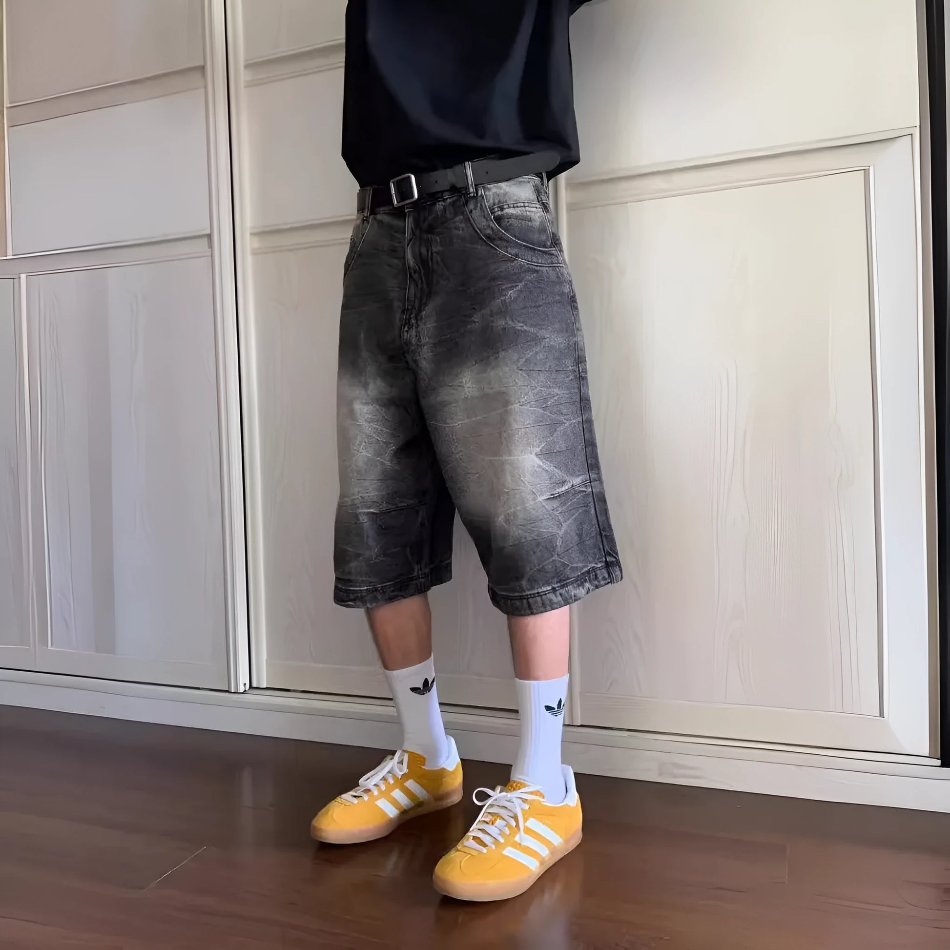 Man wearing loose light blue washed denim shorts with a straight leg and cropped length.