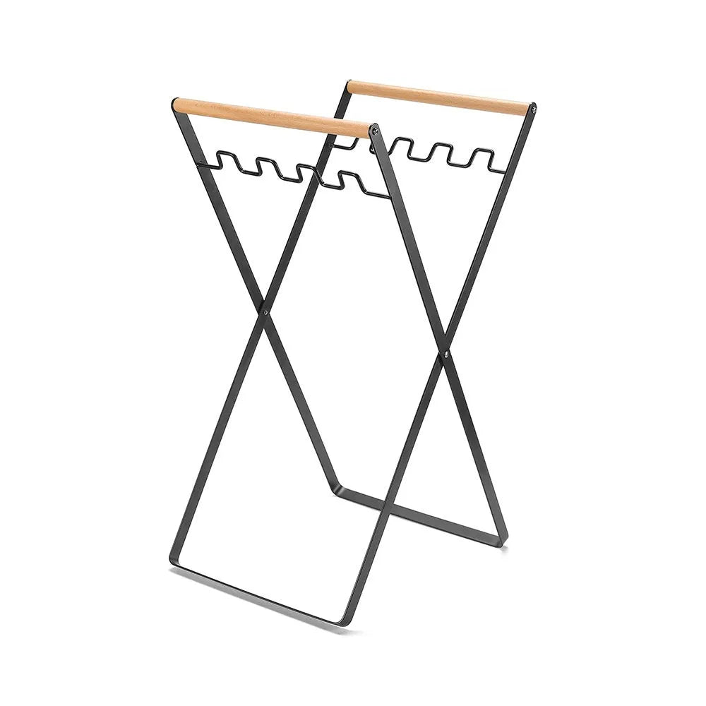 Black outdoor folding trash rack with wooden handle, holding a waste bag.