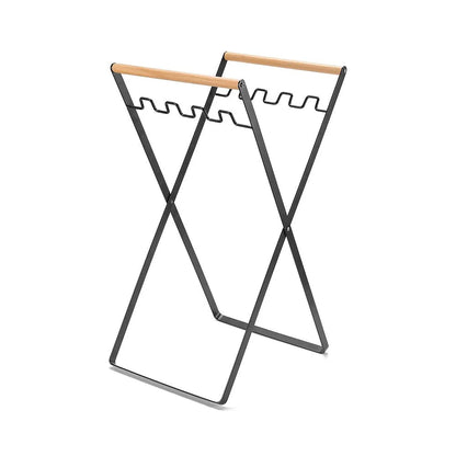 Black outdoor folding trash rack with wooden handle, holding a waste bag.