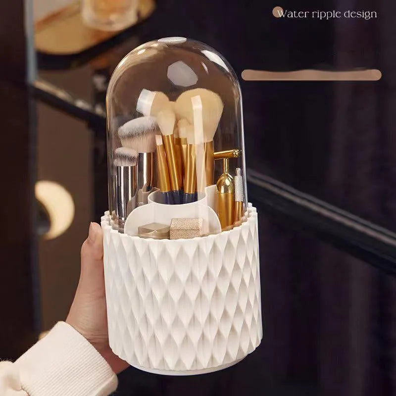 White rotating acrylic makeup brush holder with transparent dustproof lid on a desktop.