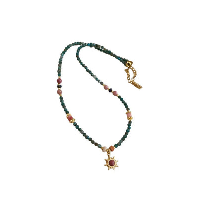 Geometric sun stone pendant on a freshwater pearl necklace with gold and blue electroplated finish.