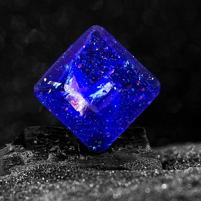 Galactic edition pocket gyro desk toy on a surface, showing its quadrilateral resin construction and celestial colour design.