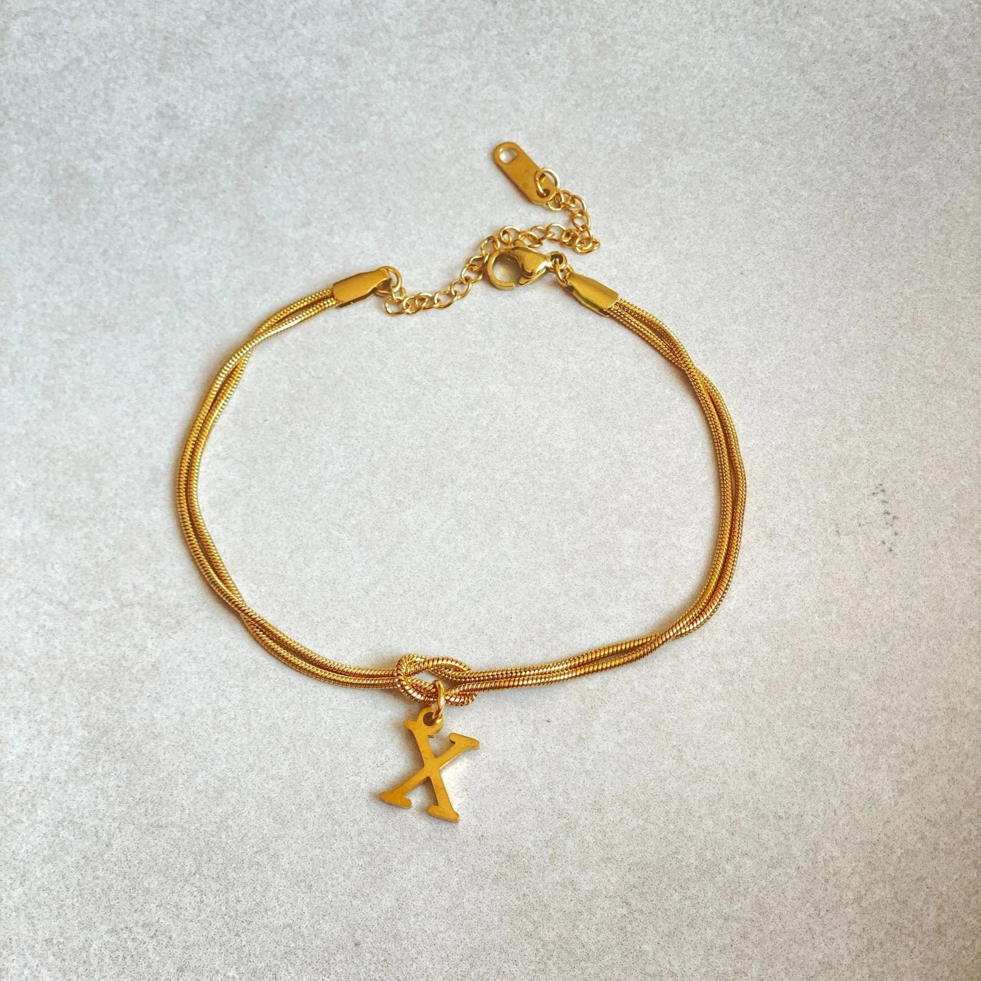 Elegant letter charm bracelets for women in gold and silver tones, featuring a delicate snake chain design and personalised letter charms.