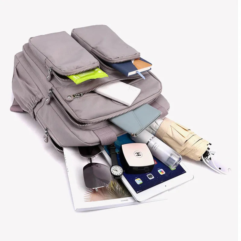 Women's waterproof nylon travel backpack in grey, showing front external pocket and organisational interior.