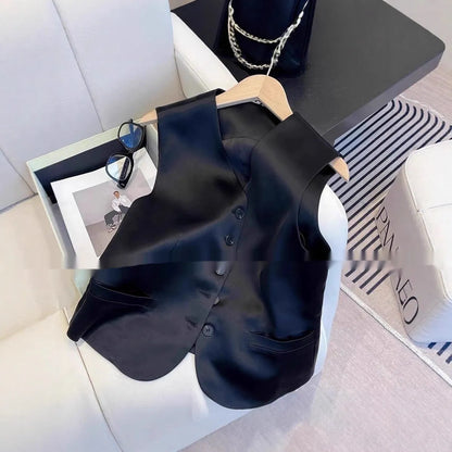 Black sleeveless satin vest for women on a hanger, showing loose fit and splicing detail.