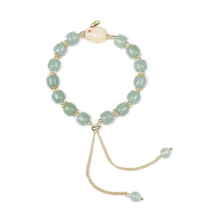 Adjustable rabbit charm bracelet with natural stone beads and gold plated details on a wrist.