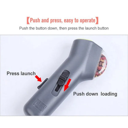 Grey-coloured pet treat catapult launcher for dogs and cats on a plain background.