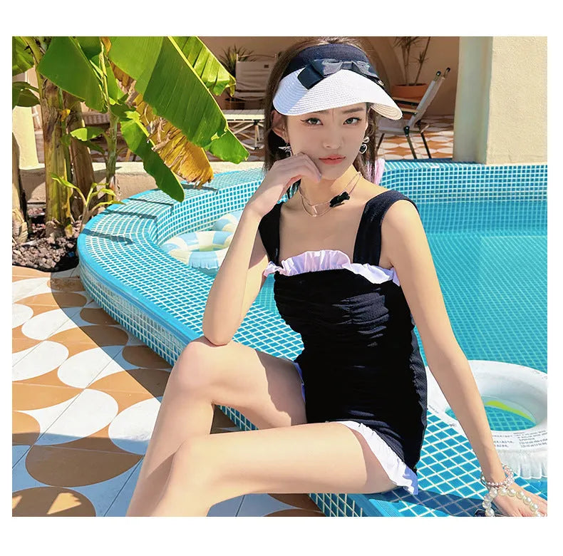 Women's solid colour one-piece swimsuit with suspender straps in a jumpsuit style.