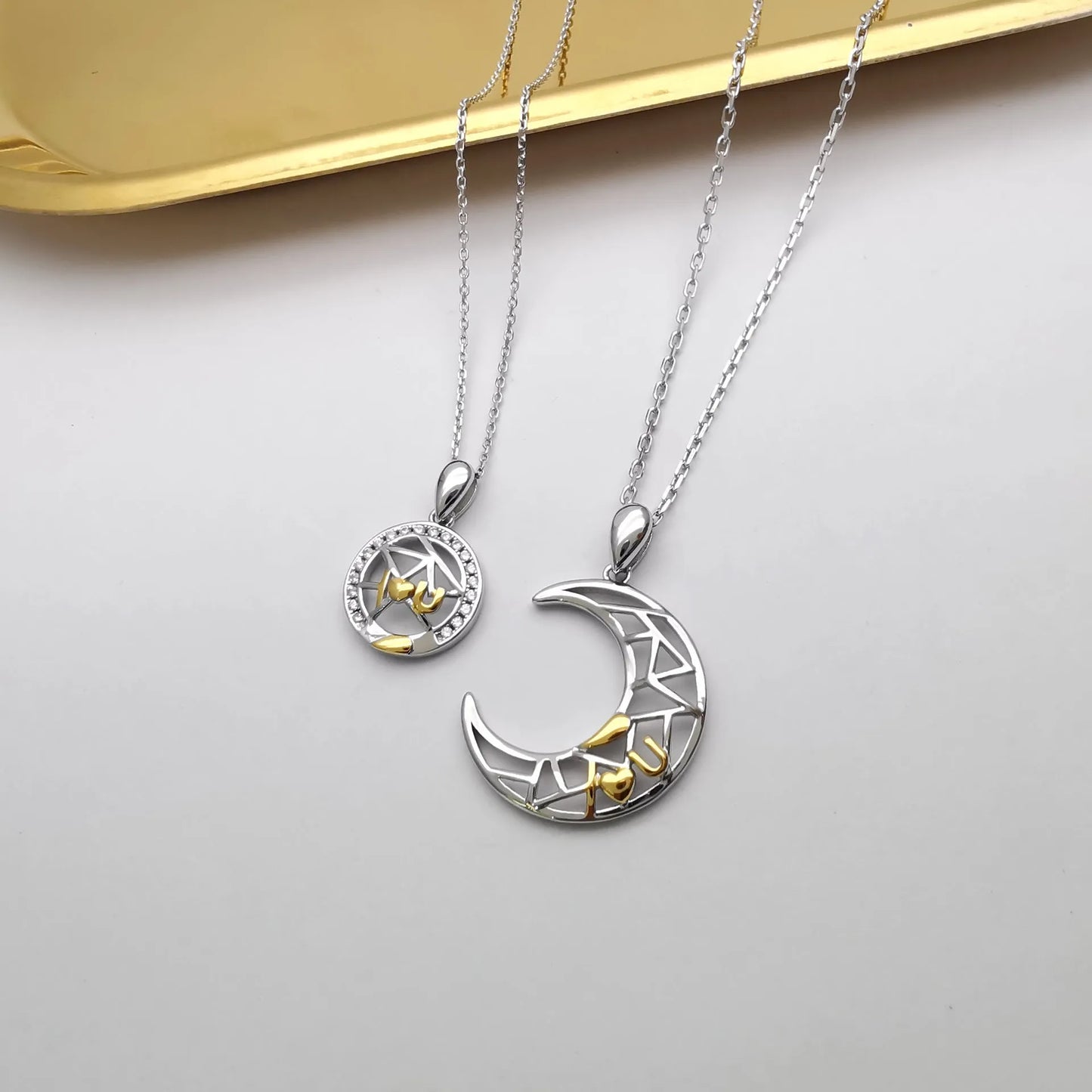 Sun and Moon copper couple's necklaces on a dark background, showing the detailed 4.5cm pendants and cross chain.