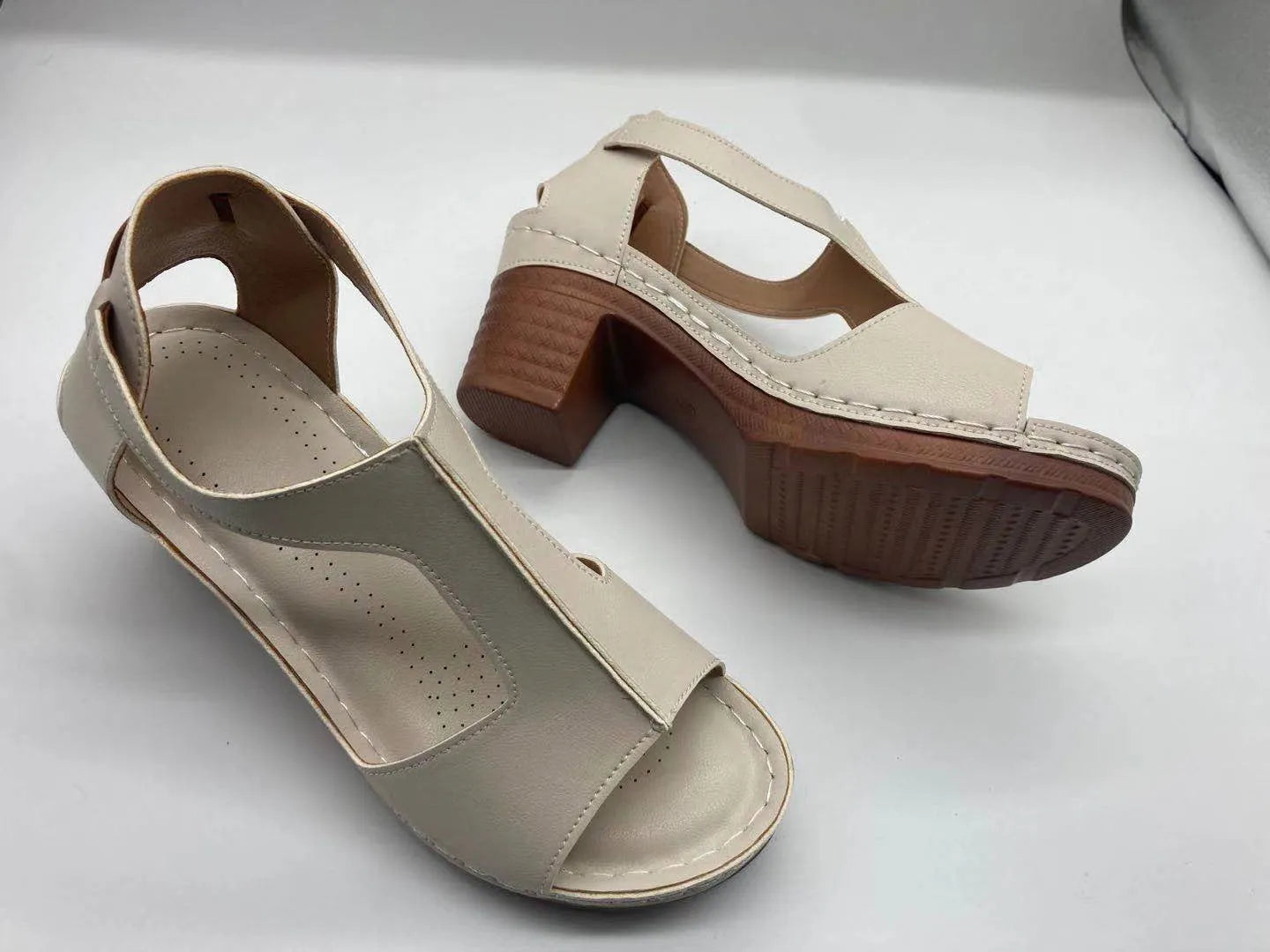 Women's beige peep toe wedge sandals with a buckle strap and low heel on a white background.