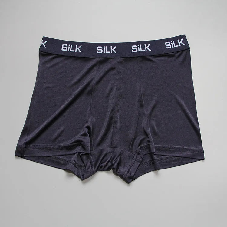 Man wearing loose-fit mid-waist shorts in navy blue silk fabric.
