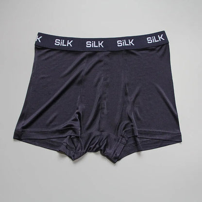 Man wearing loose-fit mid-waist shorts in navy blue silk fabric.