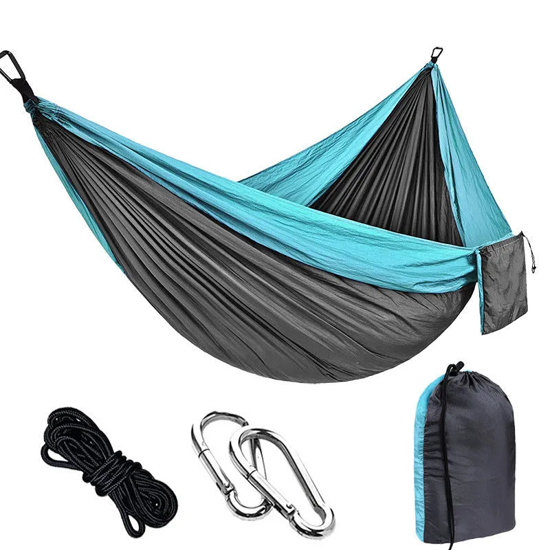 Parachute cloth double camping hammock in chosen colour, with black buckles and round ropes on a tree.
