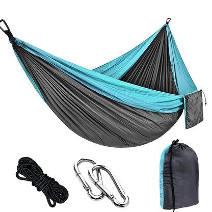 Parachute cloth double camping hammock in chosen colour, with black buckles and round ropes on a tree.
