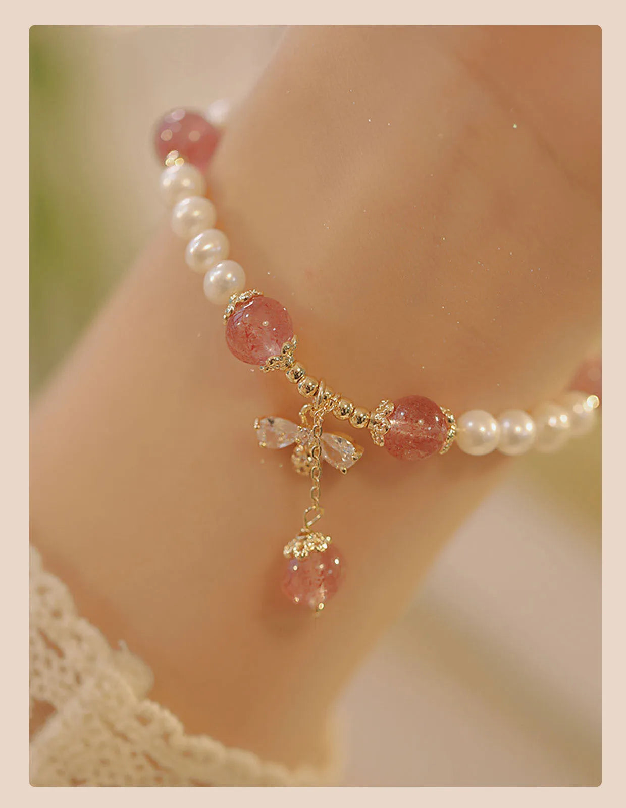 Women's strawberry quartz crystal bracelet with a decorative bow charm on a wrist.
