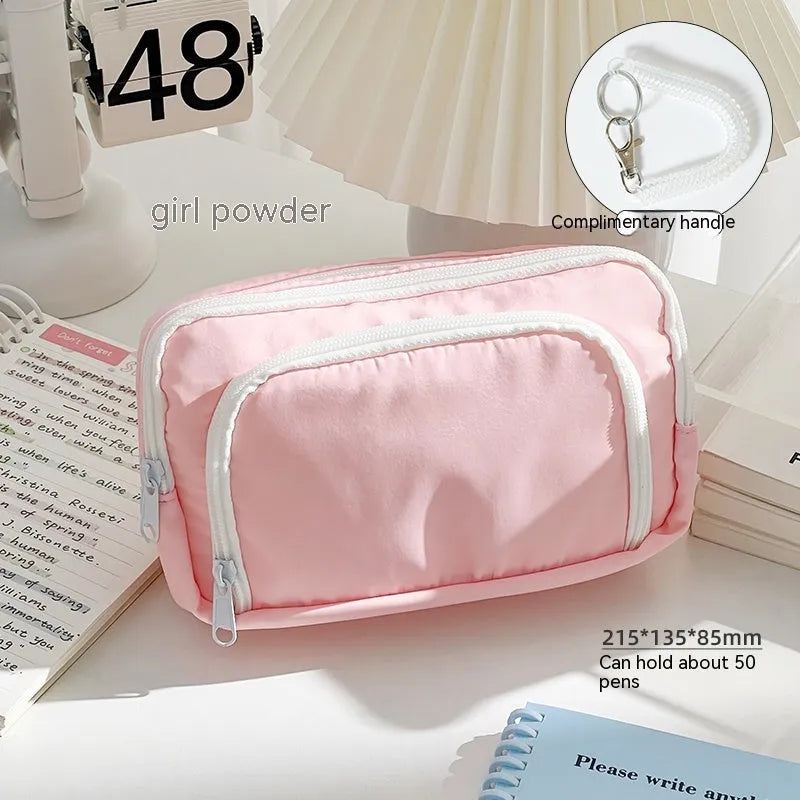 Double-layer pencil case for organising high-capacity exam stationery, measuring 215 x 135 x 85mm with a solid colour design and four colour choices including cream, pink, mint green, and clear blue.