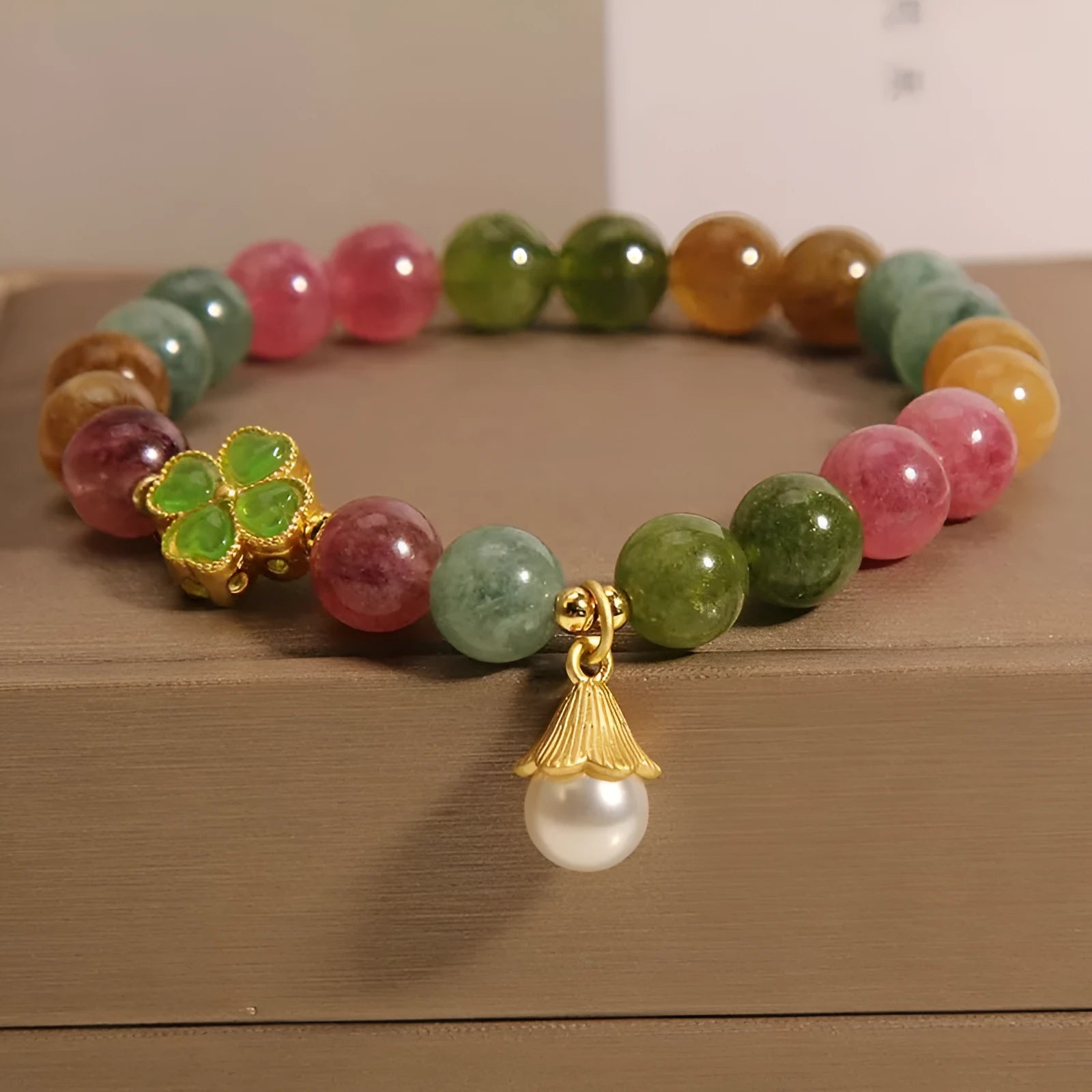 Colourful mixed-material women's bracelet with a four-leaf clover charm and a pearl pendant on a geometric chain.