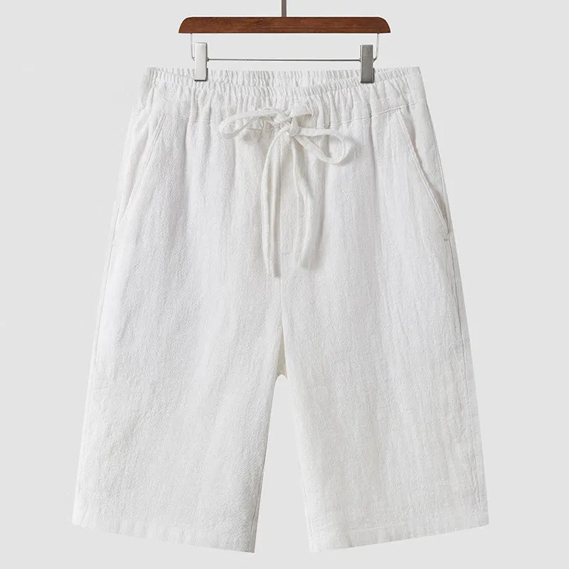 Men's beige linen casual shorts with a loose fit and elastic waistband on a neutral background.