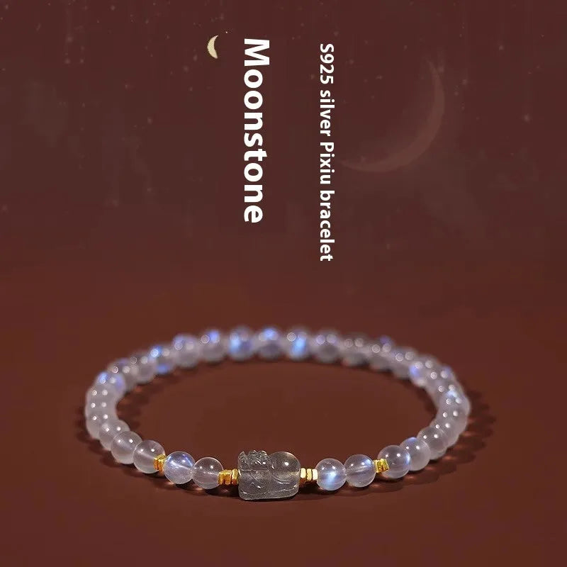 Close-up of a women's moonstone bracelet with an animal or Zodiac motif on a blue background.