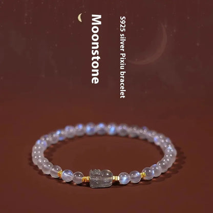 Close-up of a women's moonstone bracelet with an animal or Zodiac motif on a blue background.