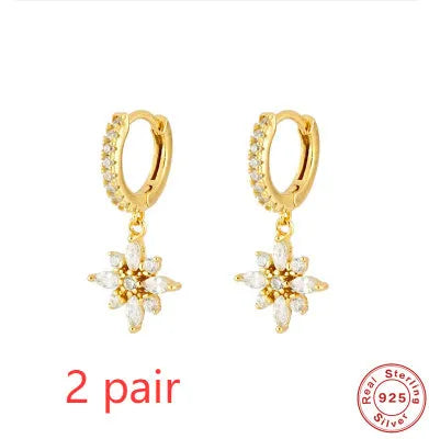 A pair of geometric snowflake pendant earrings in sterling silver with cubic zirconia stones, on a white background.