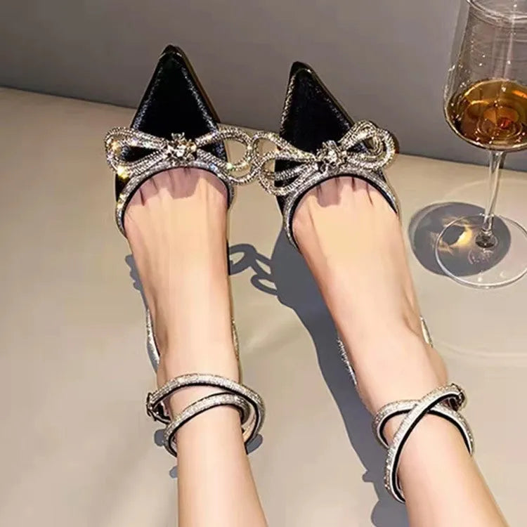 Women's black stiletto heel sandals with silk bandage ankle strap and buckle fastening on a pointed toe.
