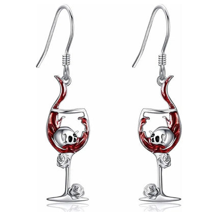 Close-up of a pair of silver-toned geometric earrings combining a skull motif with a wine glass shape.