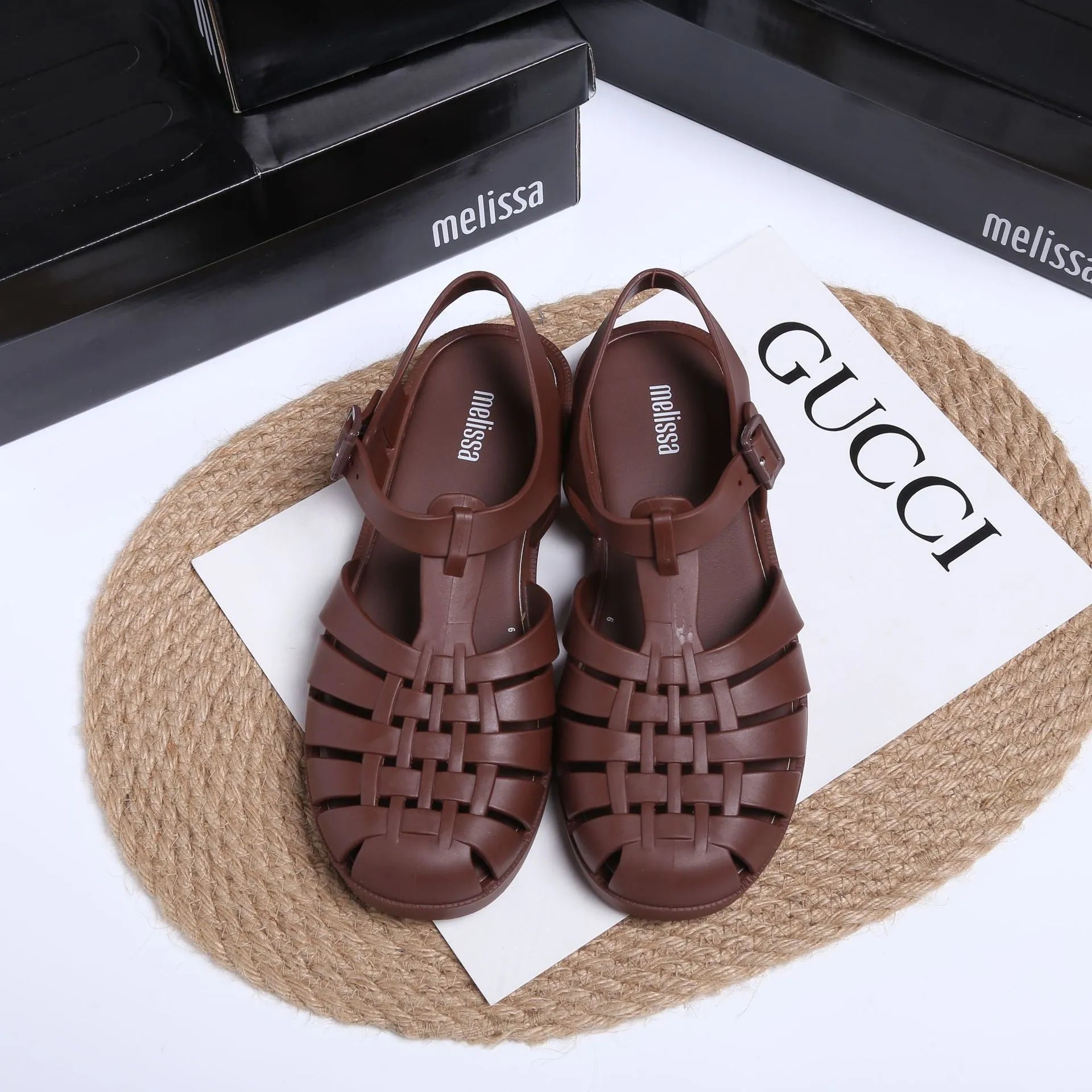 Matte black Roman sandals with vintage weave pattern, buckle fastening, and low-top PVC construction