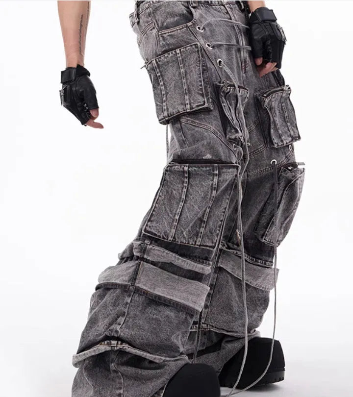 Grey distressed denim overalls jumpsuit with rope stitching on a hanger.