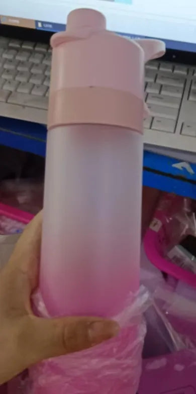 White spray water bottle with black leakproof lid and handle strap on a table