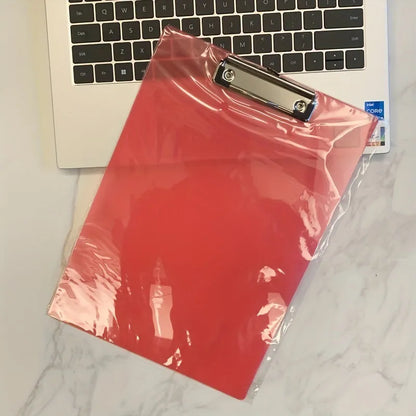 Transparent A4 plastic plate holder with metal clip, holding white paper, on a desk.