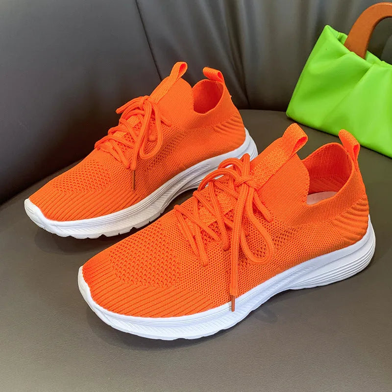 Women's running shoes in Flyknit mesh fabric with rubber sole and low flat heel for breathable casual wear, available in sizes 35-43 and colours milky white, orange, and grey