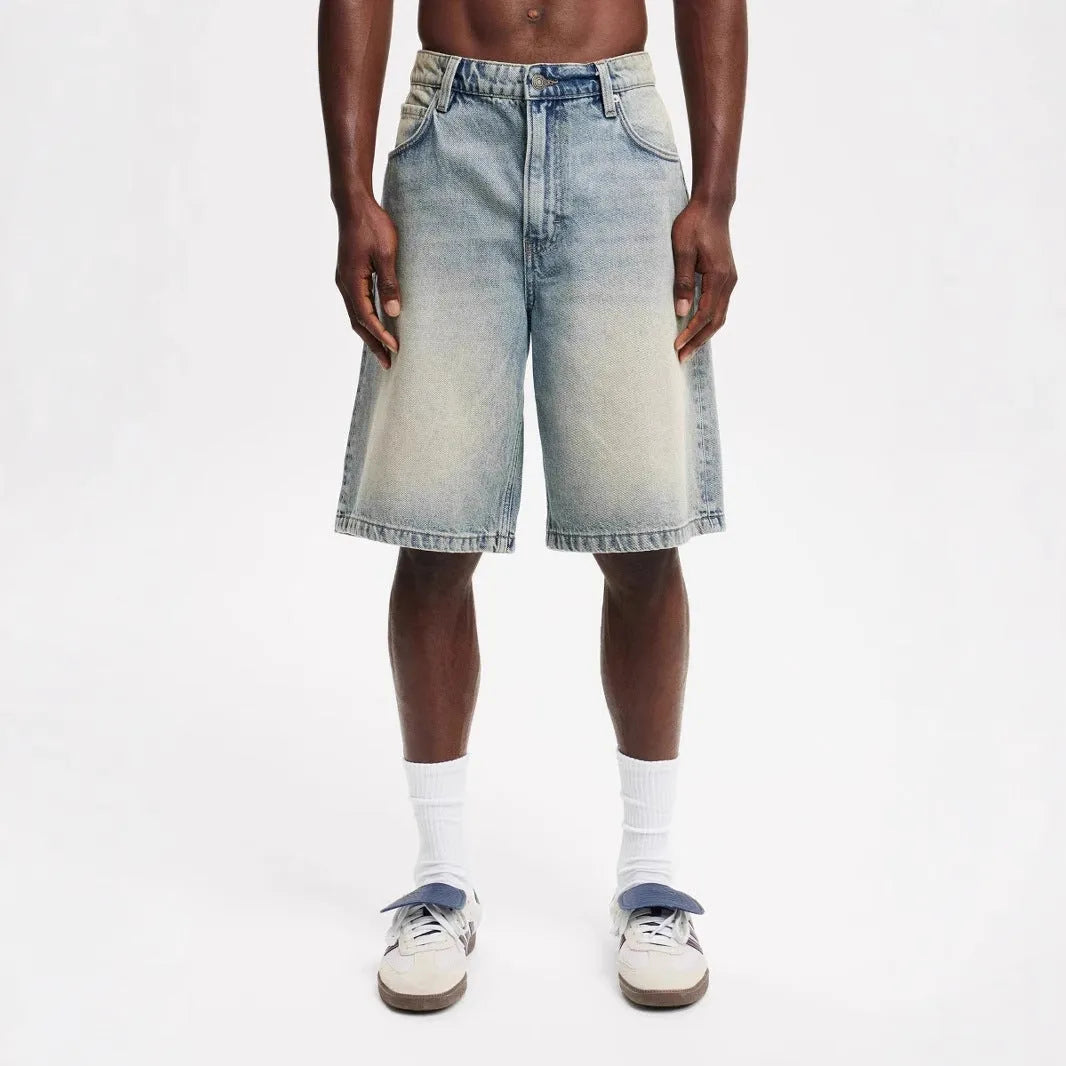 Men's light blue loose straight-leg cotton jeans laid flat, showing the front design and fifth-pants length.