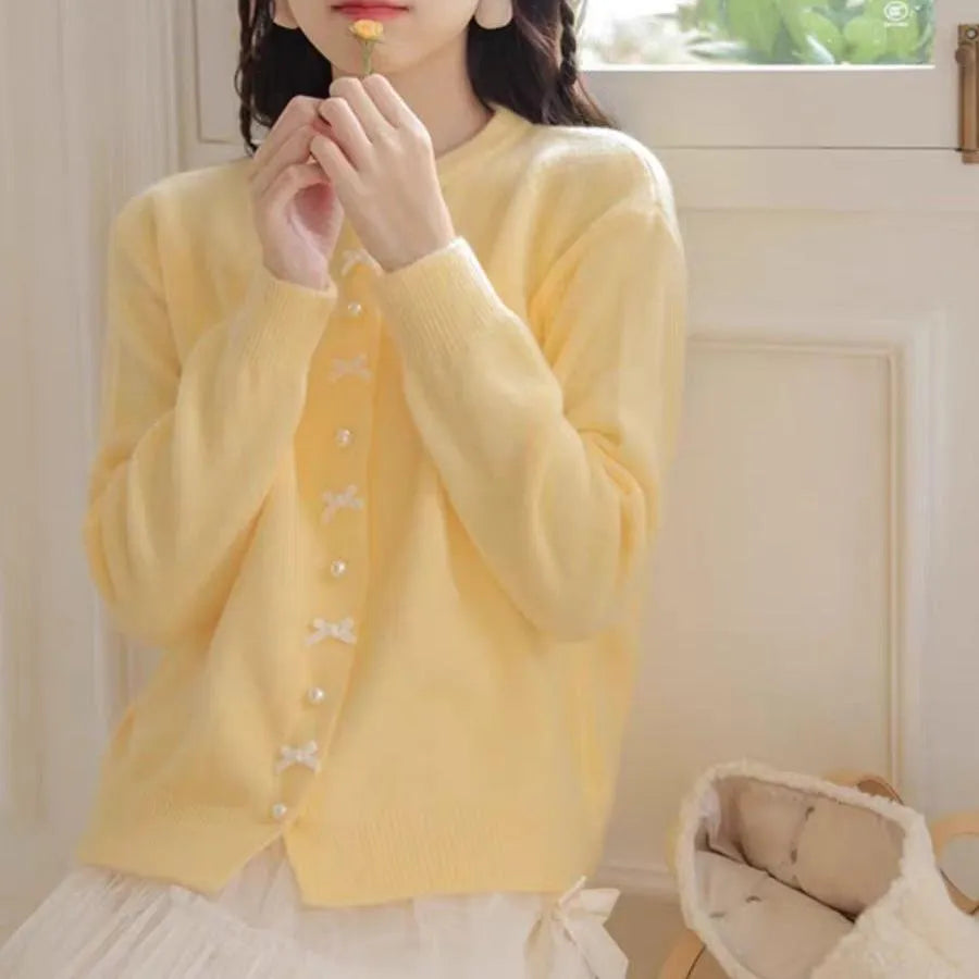 Women's acrylic cardigan sweater with pearl button bow detail in light yellow colour