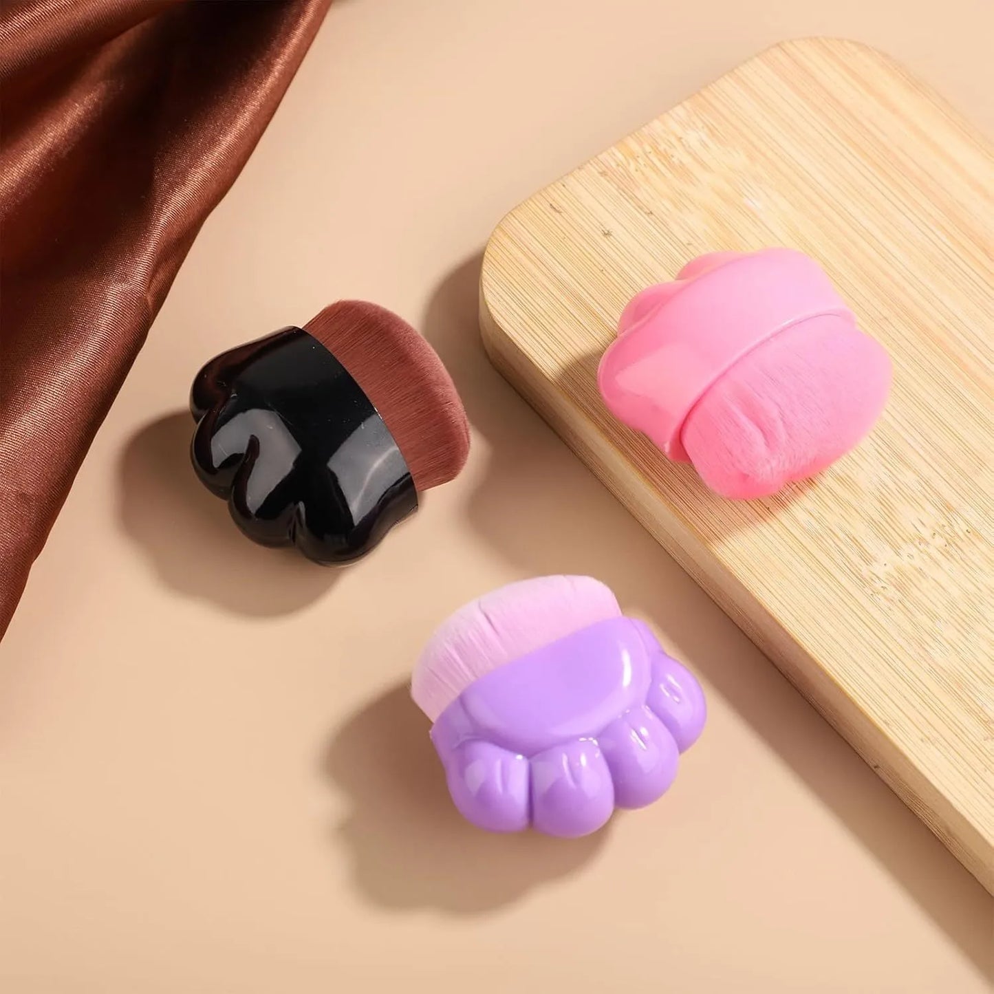 Three small paw-shaped pet balm brushes with soft heads inside clear plastic storage cases.