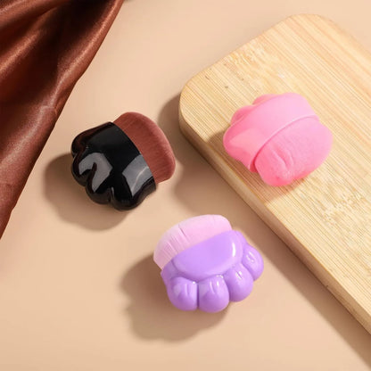Three small paw-shaped pet balm brushes with soft heads inside clear plastic storage cases.