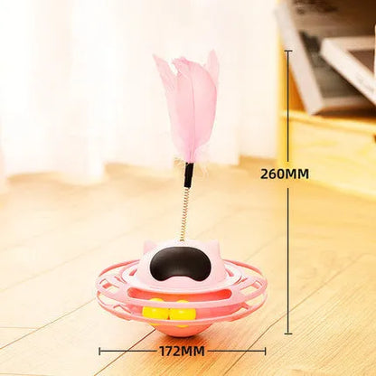 Pink self-hi tumbler cat toy with plush element on a turntable base, next to a play stick.