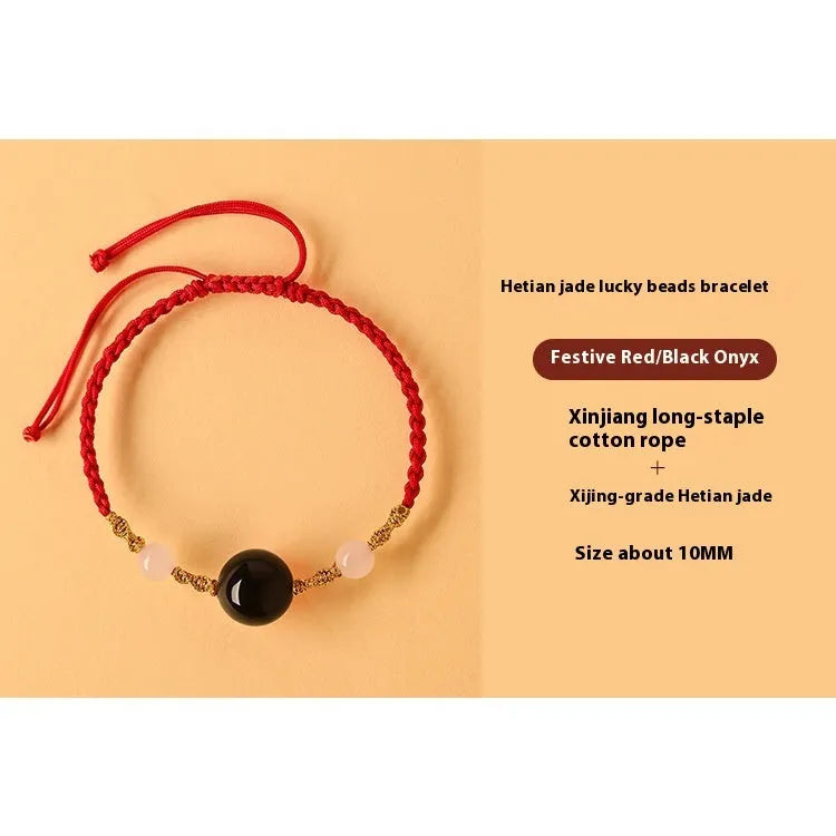 Hand-woven red rope bracelet with Hetian jade lucky beads on a wrist.