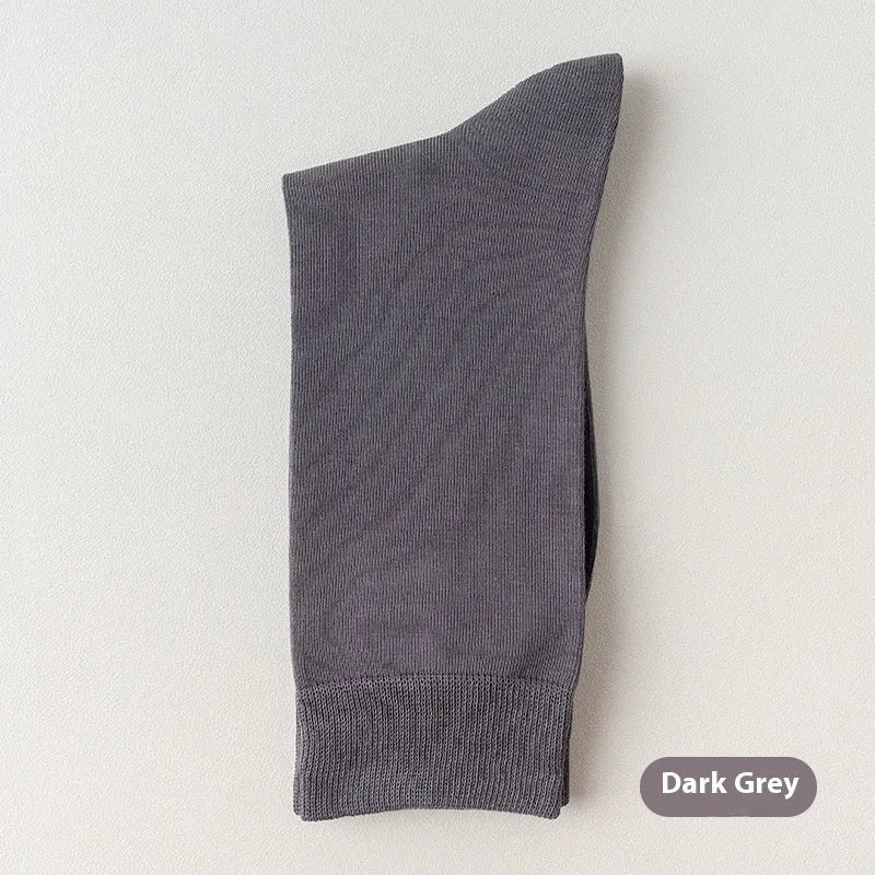 Pair of solid-colour men's mid-calf socks made from combed cotton on a wooden background