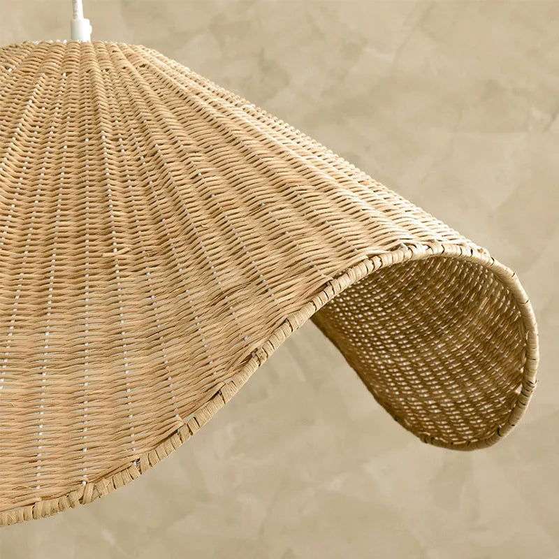 Handmade woven rattan and willow chandelier with warm LED light in a rustic setting.