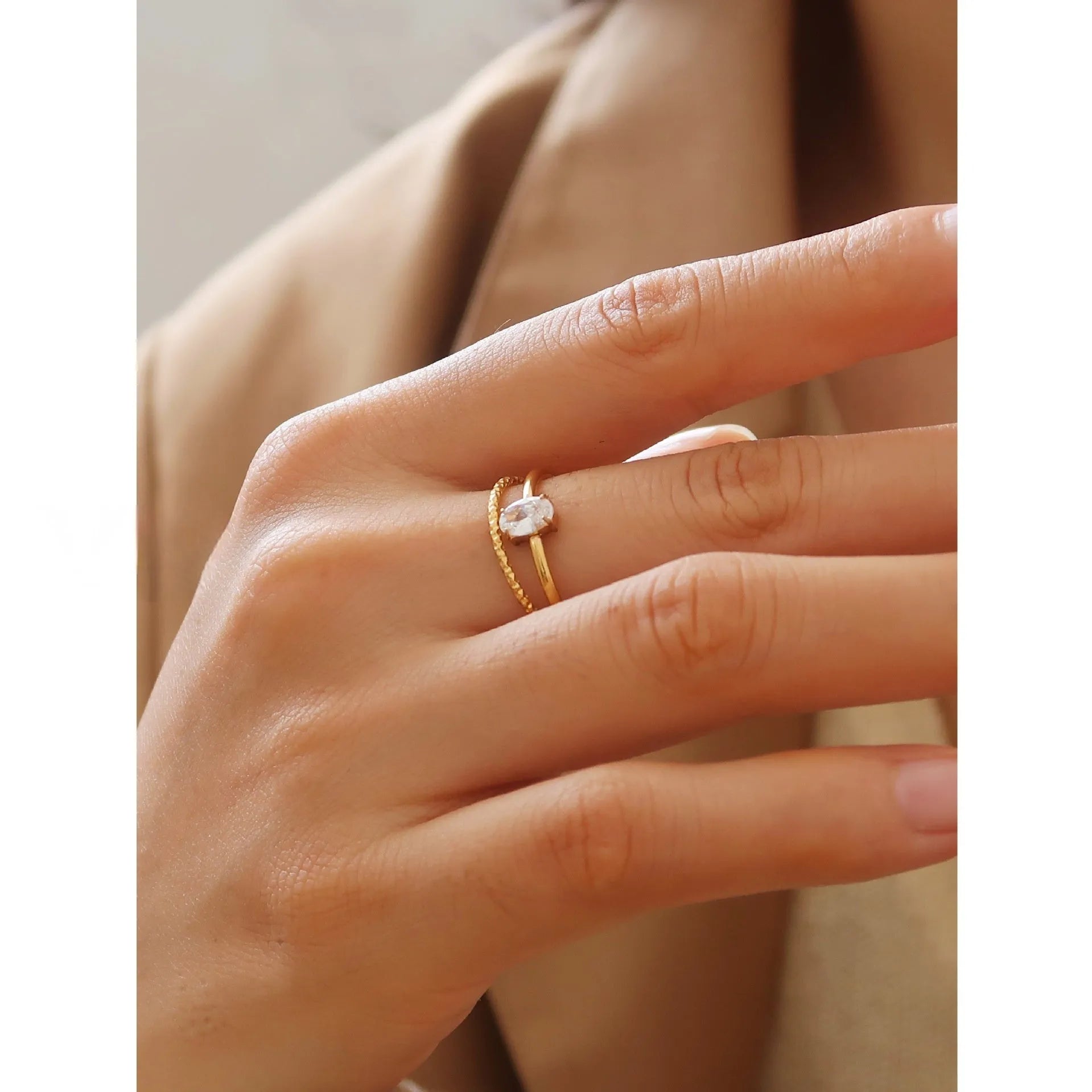 A gold-coloured stainless steel ring in a heart shape and an oval shape on a simple band.