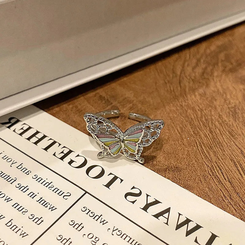 Copper butterfly women's ring with an open loop design on a plain background.
