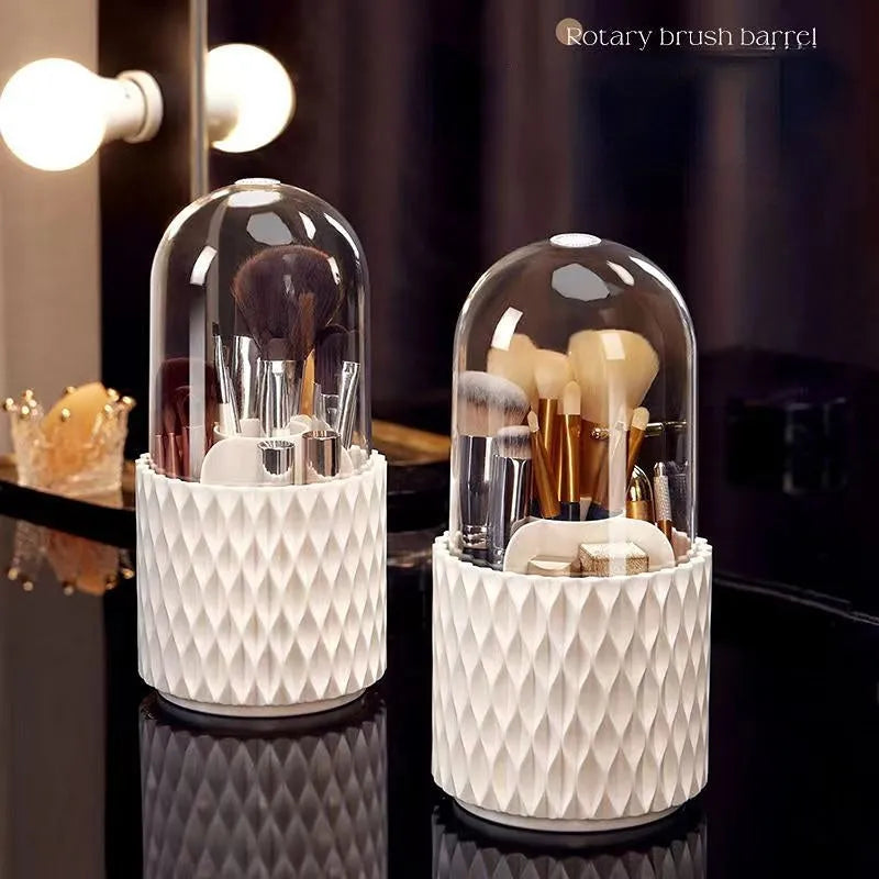 White rotating acrylic makeup brush holder with transparent dustproof lid on a desktop.
