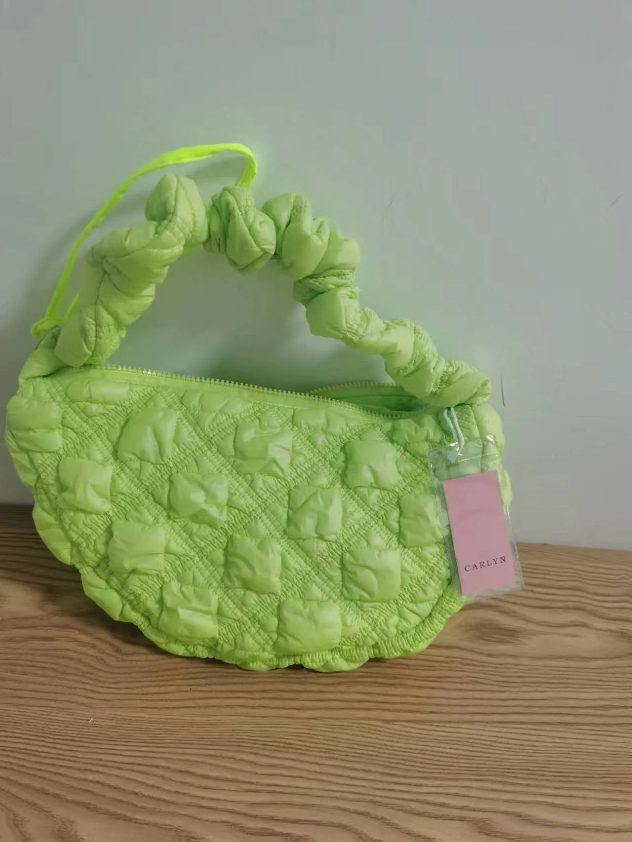 Women's light grey nylon underarm messenger bag with adjustable long strap, shown worn crossbody.
