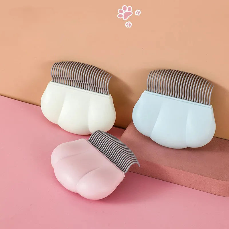 Paw Soft deshedding brush in blue, pink, or white on a wooden table with pet fur.