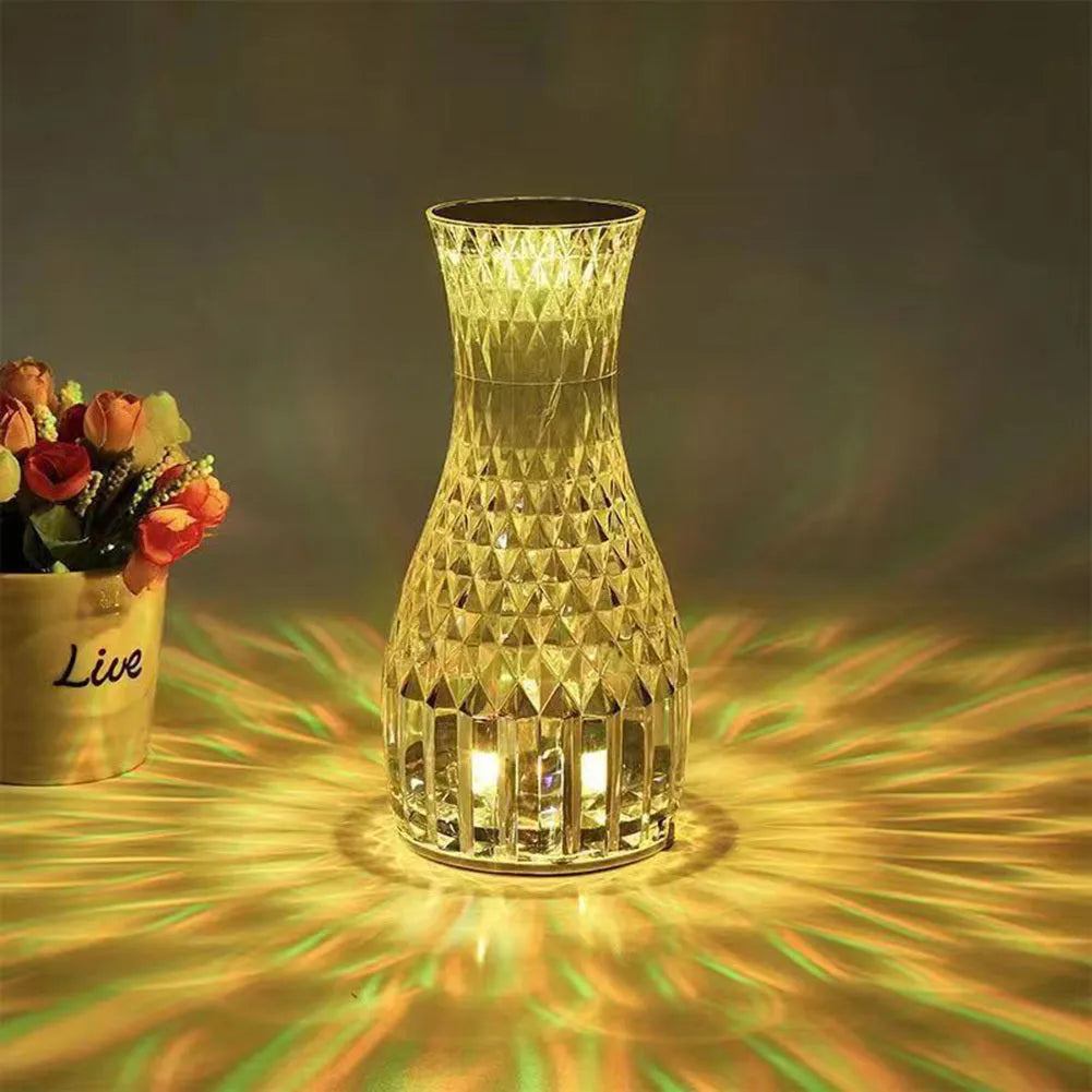 Vase-shaped crystal table lamp with remote control on a bedside table, showing diamond-like glow and USB charging port.